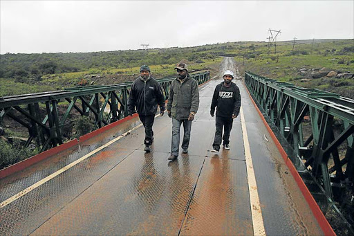 TERRIBLE LOSS: Family members of some of the 11 people who drowned at the old Cerhu river bridge walk across the new one. From the left are Bennett Vamva, Mzalwana Qutu and Thobelani Nani Pictures LULAMILE FENI .