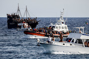 An Italian Coast Guard vessel carrying migrants rescued at sea passes between tourist boats, on Sicilian island of Lampedusa, Italy, September 18, 2023. 