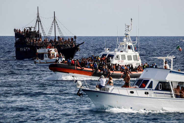 An Italian Coast Guard vessel carrying migrants rescued at sea passes between tourist boats, on Sicilian island of Lampedusa, Italy, September 18, 2023.