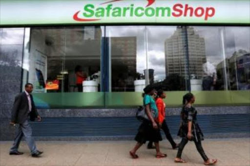 Pedestrians walk past a mobile phone care centre operated by Kenyan"s telecom operator Safaricom in the central business district of Kenya"s capital Nairobi, May 11, 2016. /REUTERS