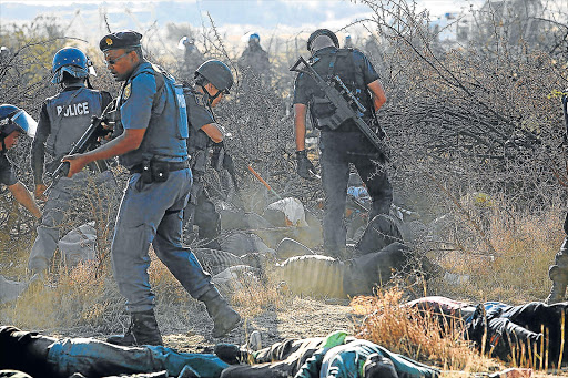 MARIKANA MAYHEM: Armed police moving among dead and wounded miners at the event after police opened fire on the strikers Picture: FILE
