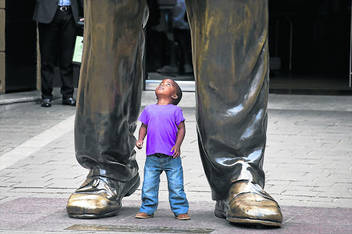 Otlile Monama, three, stands under a statue of former president Nelson Mandela , in Nelson Mandela Square. File photo.
