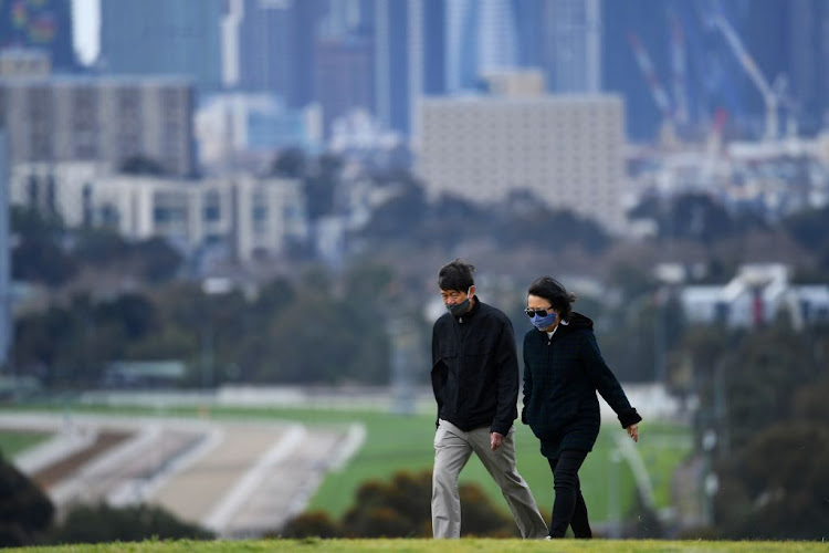 People wearing face masks walk through a park in Melbourne as the city operates under lockdown in response to an outbreak of Covid-19 in Australia, on September 2 2020.