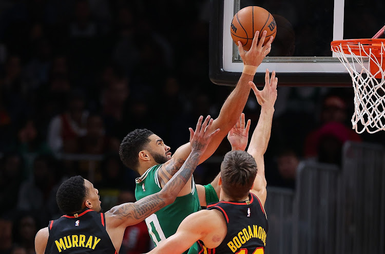 Jayson Tatum (#0) of the Boston Celtics draws a foul as he drives against Dejounte Murray (#5) and Bogdan Bogdanovic (#13) of the Atlanta Hawks during overtime at State Farm Arena on March 28, 2024 in Atlanta