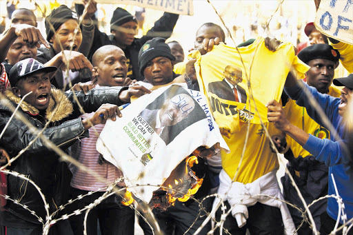 Protesters burn T-shirts bearing the image of ANC president Jacob Zuma at the Luthuli House party HQ in downtown Johannesburg in support of ANC Youth League president Julius Malema.