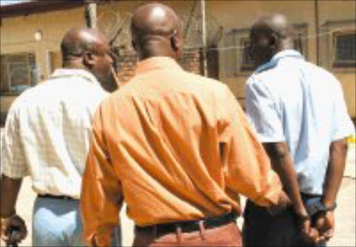 ROTTEN: An Mpumalanga constable in a full uniform on his way to the police cells after he was handcuffed by the organised crime unit on Friday. Chaperoning him are the unit's Captain Leonard Hlathi and Superintendent Petros Zimu. Pic. Andrew Hlongwane. 7/02/08. © Sowetan.