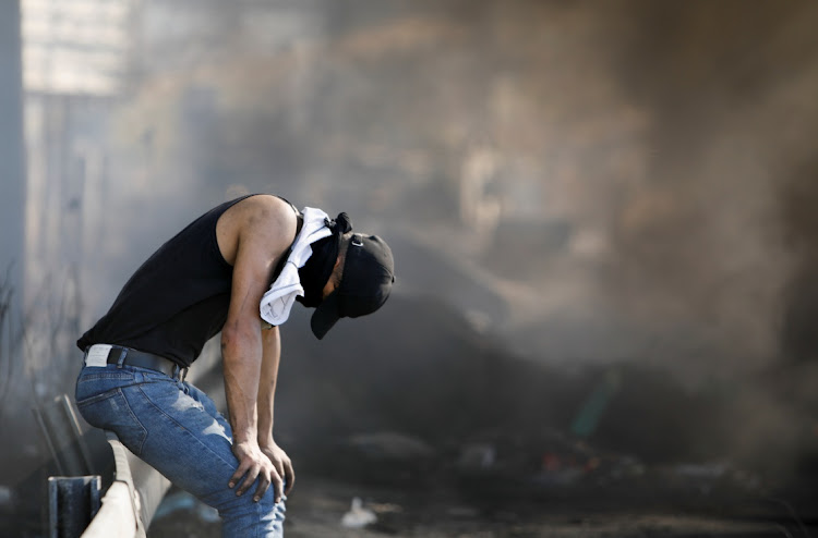 A Palestinian sits on a road rail during an anti-Israel protest over cross-border violence between Palestinian militants in Gaza and the Israeli military, near Hawara checkpoint near Nablus in the Israeli-occupied West Bank, May 18, 2021.