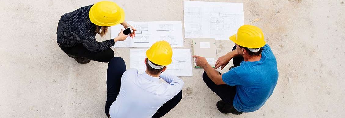 three contractors looking at building blueprints on the floor