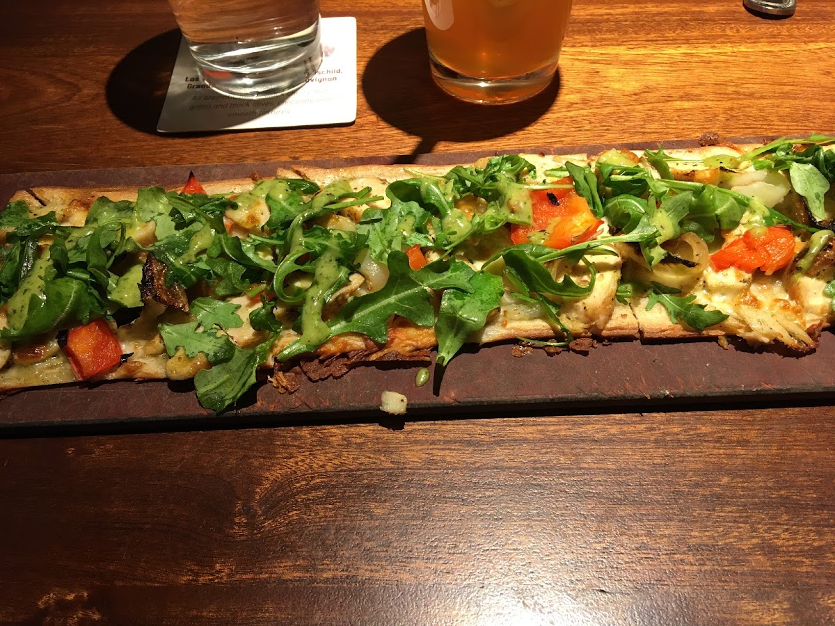 Pesto chicken flatbread with onions, red peppers and arugula