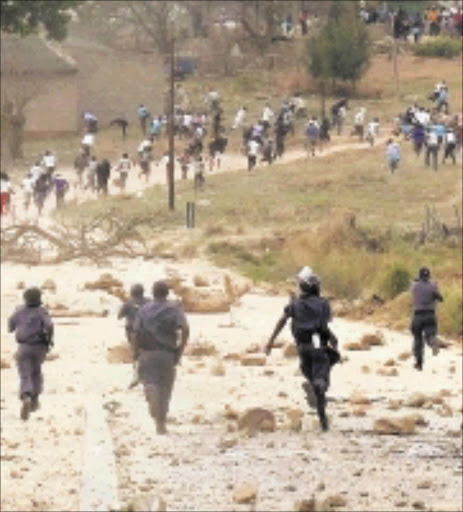 RUNNING WILD: Armed police officers chase after protesters who had been throwing stones at them yesterday. The community is demanding tarred roads at OG village near Nelspruit. Pic: RIOT HLATSHWAYO. 16/09/2009. © Sowetan.