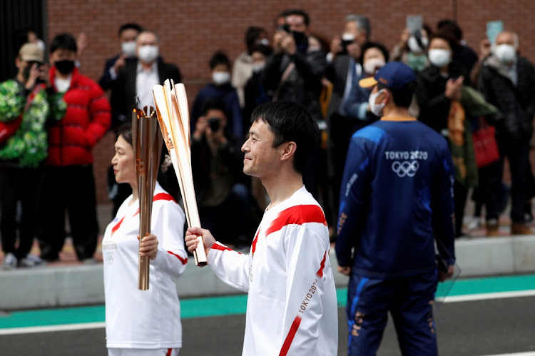 Torchbearer Junko Ito hands the torch to the next torchbearer Yoshikazu Nishikata during the Tokyo 2020 Olympic torch relay on the second day of the relay in Fukushima, Japan March 26, 2021. A fourth wave of Coronavirus is threatening the games.
