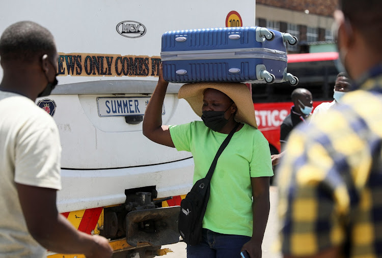 A passenger carries her luggage on her head before boarding a bus to Zimbabwe amid the spread of the Omicron variant in Johannesburg.