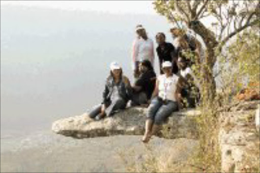 HAPPY HIKERS: The group sits in mid-air on Leopard Rock. © Sowetan.