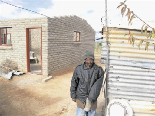 DESPAIR: Thabo Motjotji between his incomplete RDP house and the shack he currently shares with his brother. PHOTO: NTWAAGAE SELEKA