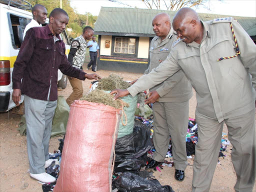 Migori county police boss Joseph Nthenge (C) and county CID Commander Benedict Kigen (R) at Migori police station with part of Sh60m bhang concealed in bales of Mtumba. /MANUEL ODENY