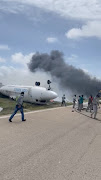 Firefighters spray water on a plane that flipped over after a crash landing, in Mogadishu, Somalia, July 18, 2022, in this screen grab obtained from a social media video obtained by Reuters.  