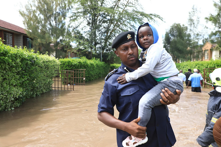 A security guard carries a child out of a residential estate affected by the floods in Athi River, Machakos on April 24, 2024.
