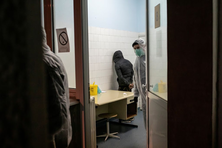 Police officers in protective suits detain a migrant who is suspected of having Covid-19 at the infection clinic in Belgrade, Serbia, on March 17 2020.