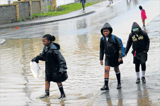 DRENCHED: Most school pupils in the East London townships were sent home during yesterday’s heavy rains. Here children are seen at Nompumelelo township Picture: MICHAEL PINYANA