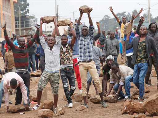 Supporters of opposition leader Raila Odinga hold up boulders in front of a barricade in Kawangware slum in Nairobi, Kenya. REUTERS/Goran Tomasevic