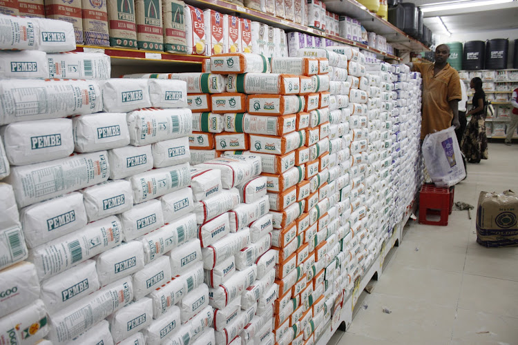A shop attendant arranges packets of maize flour in a supermarket shelf/