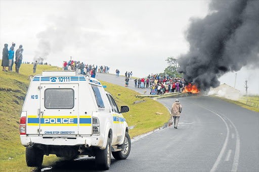 ON THE WARPATH: Angry Mqanduli youths, armed with sticks and pangas, block the road with burning plastic water pipes that were part of a water provision project yesterday Picture: SIKHO NTSHOBANE