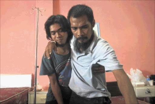 TAKING THE STRAIN: Released Filipino hostages Roland Letrero, left, holds Ramil Vela as he tries to stand up in a hospital in Sulu, southern Philippines. Gunmen belonging to a militant Islamist group freed the two Filipino television crew yesterday. photo: REUTERS