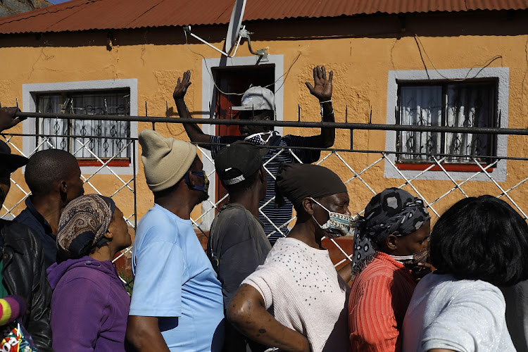 People queue for food parcels in Kliptown, Soweto. Many South Africans have lost their jobs and businesses during the pandemic. File photo.
