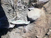 A wrapper bearing the name of clothing retailer Ackermans lies in the dust at the spot next to the N1 where a truck full of garments was looted on Sunday May 12.