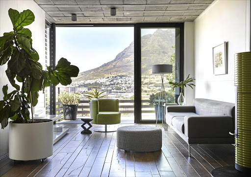 The lounge area boasts city and mountain views. The couch and swivel chair are from Comfort Creations; the ottoman and standing lamp are from LIM, and Sandra posted the wooden stool home from Zimbabwe. The painting is by Sandra’s aunt.