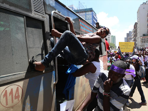 A lady hangs from an Embassava matatu when women held a protest along city streets over the stripping of a woman by conductors for alleged indecent dressing.Photo/HEZRON NJOROGE