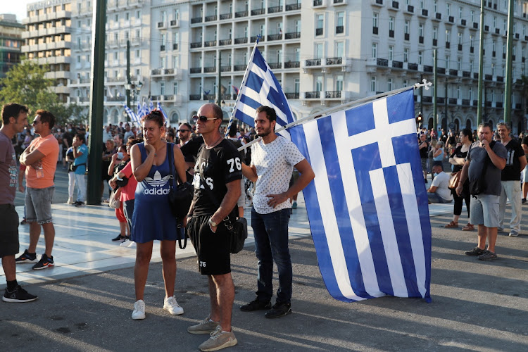 People hold Greek flags during a protest against coronavirus disease (Covid-19) vaccinations outside the parliament building, in Athens, Greece, August 29, 2021.