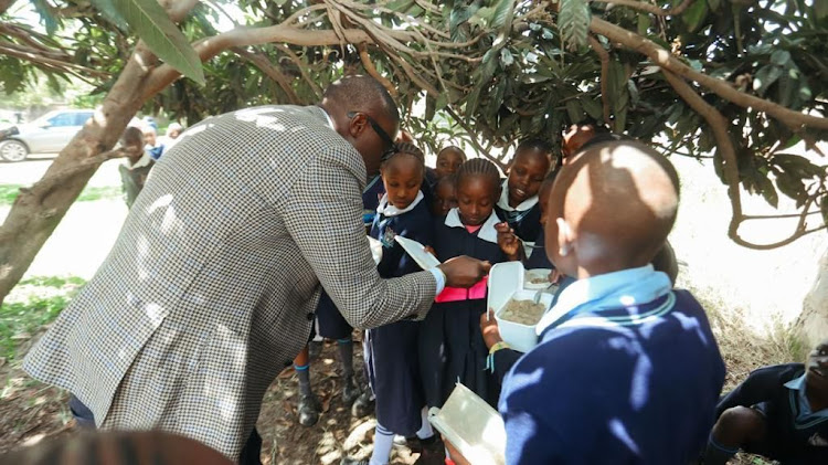 Nairobi Governor Johnson Sakaja engaging with pupils as they have meal of the Dishi na County programme at Kinyanjui Primary School on January 8, 2024.