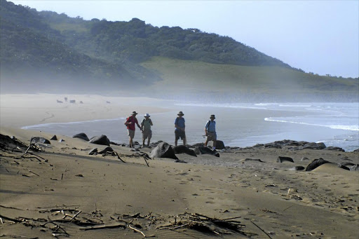 Hikers make their way along an empty, pristine beach on the way to Kei Mouth.