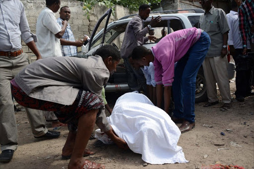 Residents of Mogadishu remove the body of female MP and former singer Sado Ali Warsame after gunmen opened fire at her car on July 23, 2014 killing her and her driver in Somalia's capital Mogadishu.