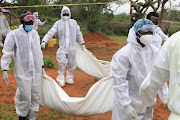 Forensic experts and homicide detectives carry the bodies of suspected members of a Christian cult in Kenya who believed they would go to heaven if they starved themselves to death.