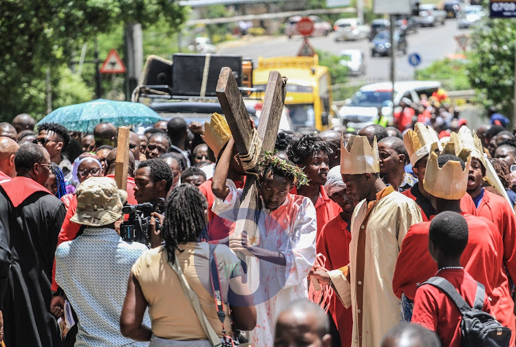 A catholic faithful carries a cross along Arboretum Road in Nairobi during the Way of the Cross reenactment on April 7, 2023.