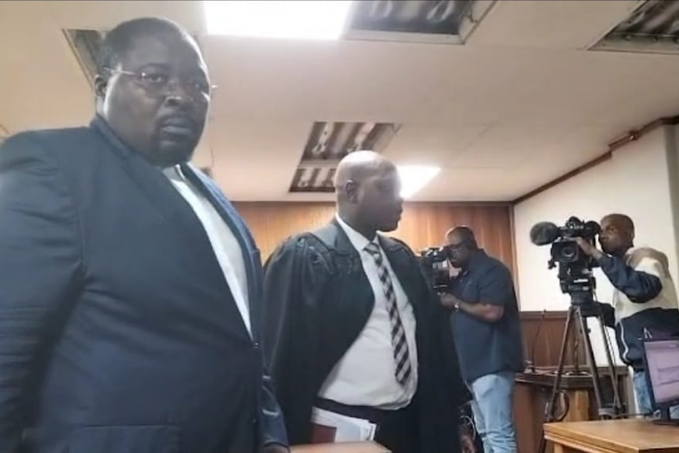 Former Tshwane mayor Murunwa Makwarela, left, walks out of the Pretoria specialised commercial crimes court on Tuesday after the matter was postponed due to him failing to brief his legal team ahead of the court date.