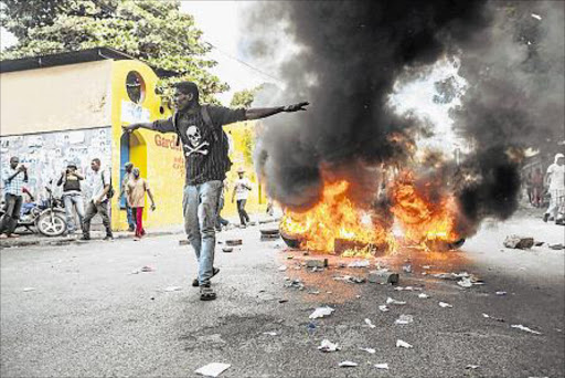 ABLAZE: A protester reacts in front of a pile of burning tires during a demonstration as thousands of protesters took to the streets of Port-au-Prince, Haiti, 23 January 2016. Gun shots were heard and tear gas was shot by riot police as protesters threw stones at the police and set tires on fire. The demonstrations continued despite the fact that Haitian officials have cancelled the presidential run-off election scheduled for 24 January, just days ahead of the vote