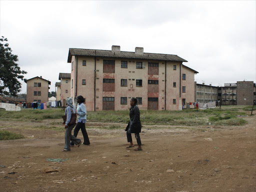 People walk past the railway housings at Makongeni in Eastlands Nairobi