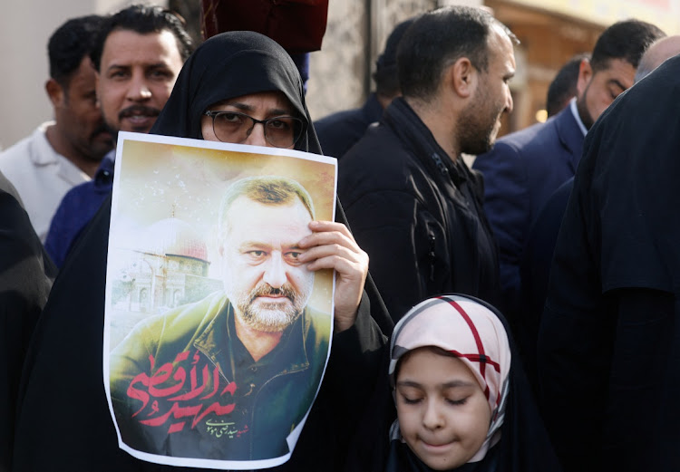 A woman holds a picture of senior adviser for Iran's Revolutionary Guards, Sayyed Razi Mousavi, who was killed in an Israeli air strike outside the Syrian capital Damascus, during his funeral in Najaf, Iraq, on December 27 2023.