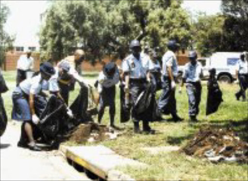 CIVIC DUTY: Police officers pick up litter in the streets of Vereeniging yesterday during a campaign to discourage people from littering. Pic. Len Kumalo. © Sowetan.