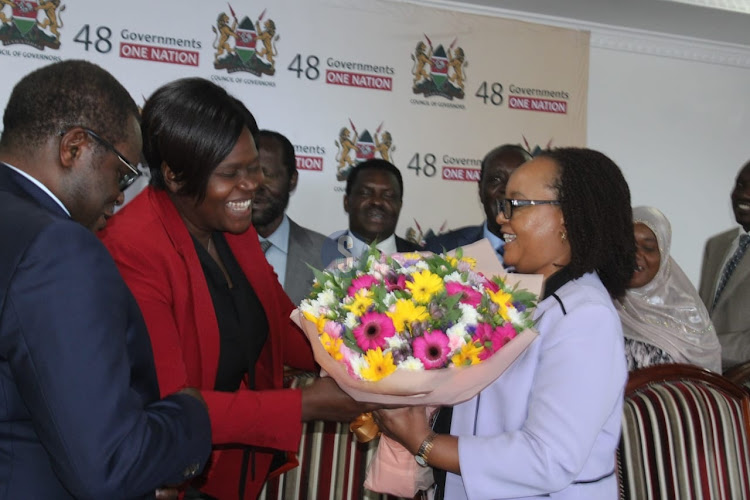 Homa Bay Governor Gladys Wanga hands a bouquet of flowers to Council Chair Anne Waiguru as a surprise to celebrate her birthday after a full council meeting to discuss the ongoing doctors strike at the COG headquarters in Nairobi on April 16, 2024