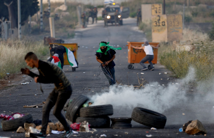 Palestinians run from Israeli forces during a protest. Picture: MOHAMAD TOROKMAN