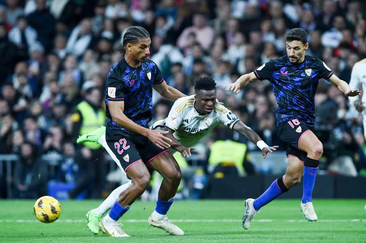 Real Madrid's Vinicius Junior (C) vies with Sevilla F.C.'s Loic Bade (L)