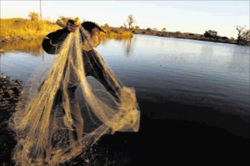 FEARLESS: A fisherman Rofhiwa Mulaudzi, 18, from Tshilungoma village outside Thohoyandou in Limpopo, he believes to catch fish at sunrise and sunset by using his cast net at the biggest dam Nandoni in Limpopo. Thirteen fishers were reported drowned in this dam and mauled by crocodiles. Pic: Elijar Mushiana. © Sowetan.