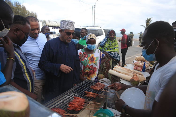 KenTrade chairman Suleiman Shahbal buys mshikaki from a trader at Light House near the Mama Ngina Waterfront Park on Friday.
