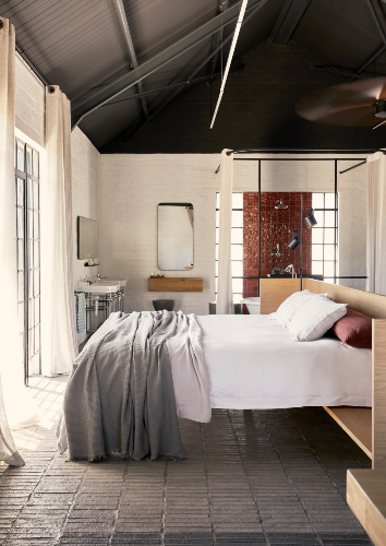 The gentle return on the headboard contains the bed – a smart design solution that gives one the sense that it is a defined sleeping zone in the open-plan cabin. The ceiling was painted in a black finish to hide the fans and beams, leaving a small 3m ceiling line that was kept light with whitewashed brick walls.