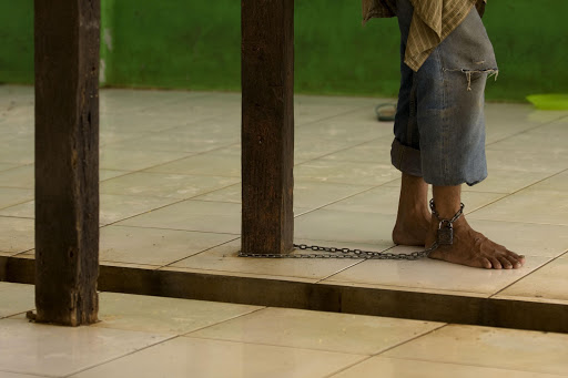 BEKASI, INDONESIA - FEBRUARY 10: The leg of a patient is chained to a post at the Galuh foundation for people with mental health conditions on February 10, 2010 in Bekasi, Indonesia. Belief in black magic is commonplace in Indonesia, where there is much ignorance over mental health issues, with traditional healers instead consulted for apparent sufferers. 2007 figures suggested that 4.6% of the nation suffered from serious mental disorders in a country whose population now stands at around 230 million, with only around 700 psychiatrists across 48 psychiatric hospitals available to help treat those affected. With such limited care, sufferers are instead usually believed to be affected by black magic and thus taken to 'dukuns' or healers believed to have magical powers.