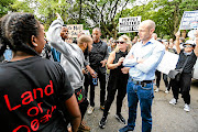 STAND-OFF: Black First Land First members clash with #saveasouthafrica  members outside the Gupta compound in Saxonwold, Johannesburg. BLF members argued that white people should not  attack the family 'because  white people  own most of the companies on the JSE'. The group  held up signs saying '#HandsOffZuma'.
